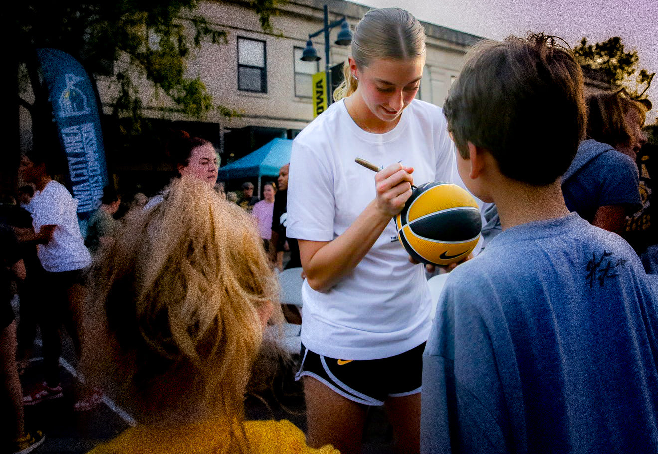 Person signing a sports ball for a young fan outdoors