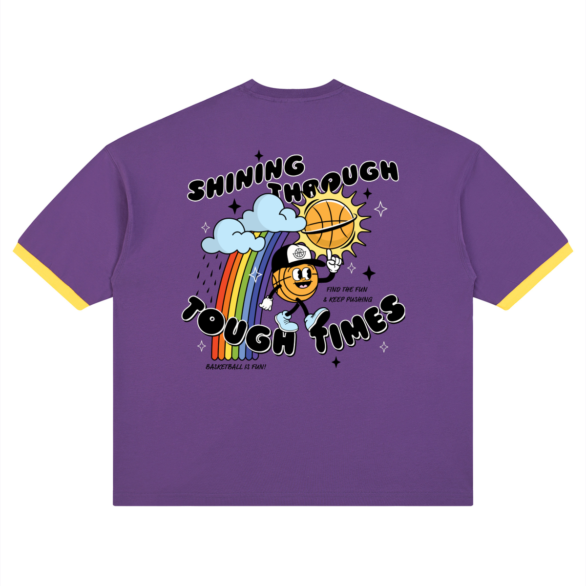 A purple ringer t-shirt with yellow trim on the sleeves and hem, featuring a colorful cartoon graphic of a basketball mascot holding a basketball under a rainbow and clouds with the text 'SHINING THROUGH TOUGH TIMES'.
